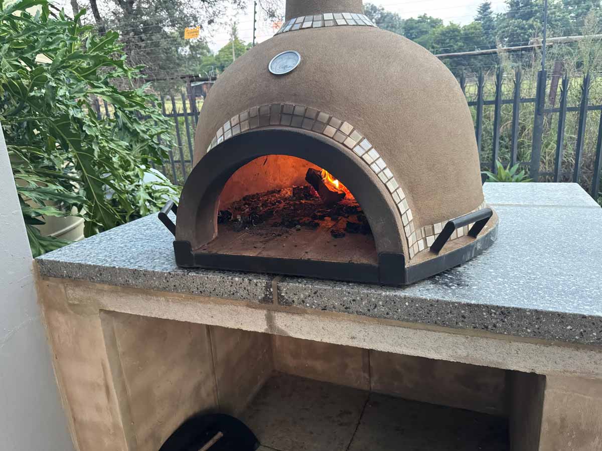 Easy Edge SA wood-fired pizza oven alight on custom clad counter – front view